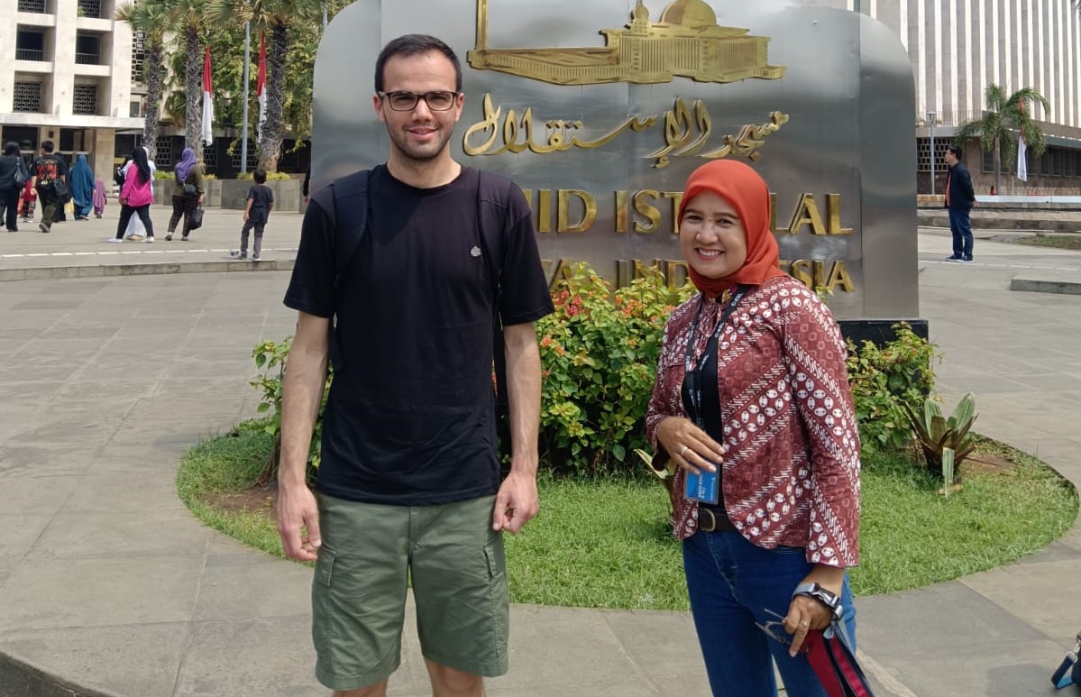 Young female Indonesian tour guide with backpack leading group through rice fields